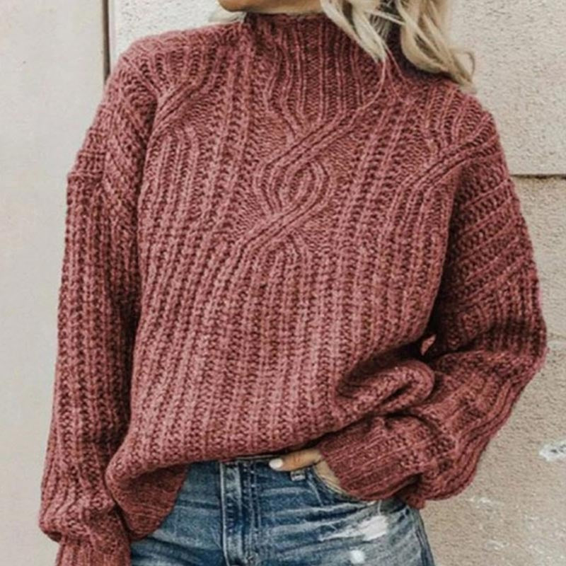 Grobstrickpullover mit Zopfmuster und Stehkragen in Ziegelrot, zu Jeans mit Rissen getragen