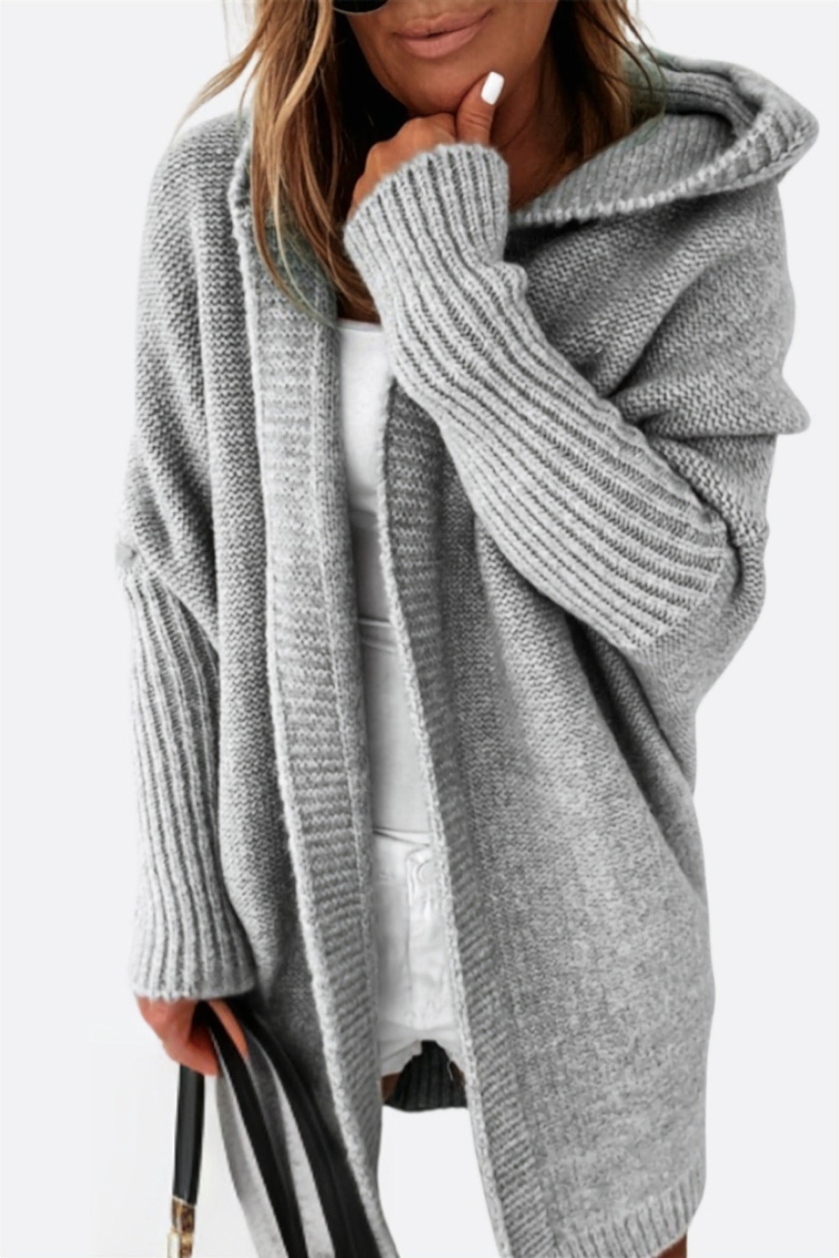 Graue lange Strickjacke mit Kapuze, offen über einem weißen Top getragen