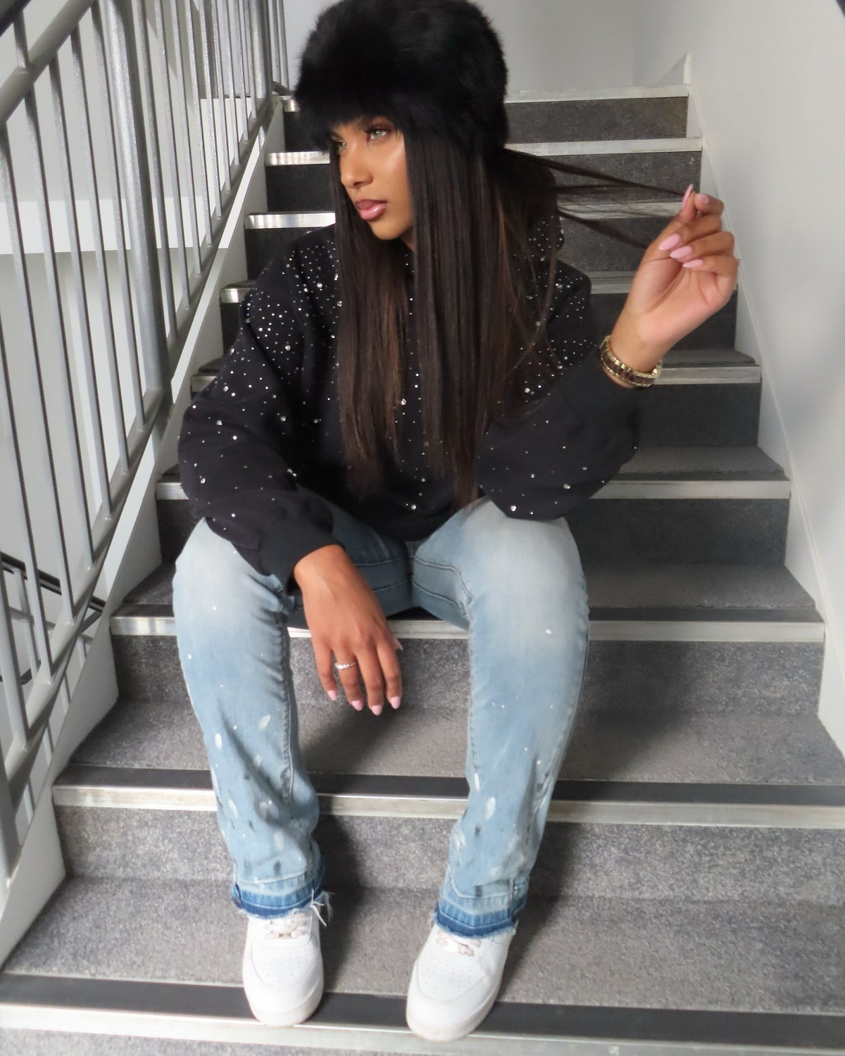 Frau im schwarzen Strass-Hoodie auf einer Treppe