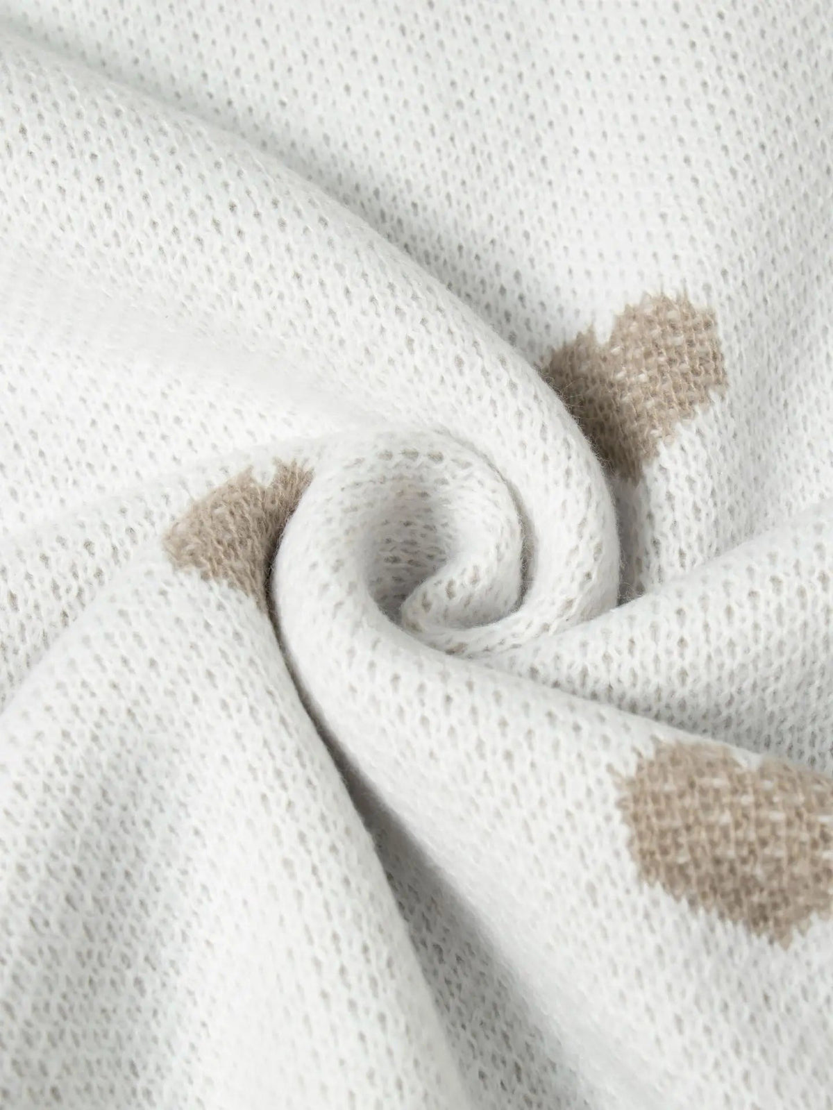 Nahaufnahme des Strickmusters mit beigefarbenen Herzen