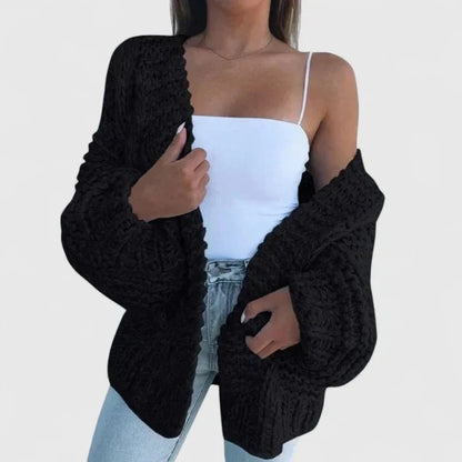 Oversize-Grobstrickjacke in Schwarz, offen über einem weißen Top getragen