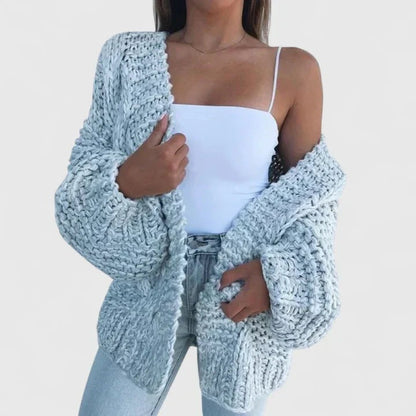 Oversize-Grobstrickjacke in Hellblau, offen über einem weißen Top getragen