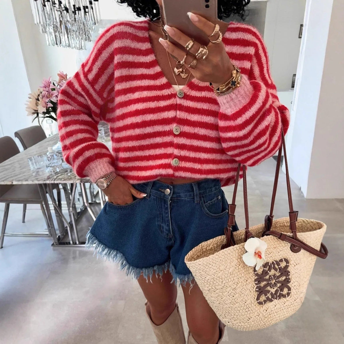 Gestreifte Oversize-Strickjacke in Rot und Rosa mit V-Ausschnitt, zu Jeansshorts getragen