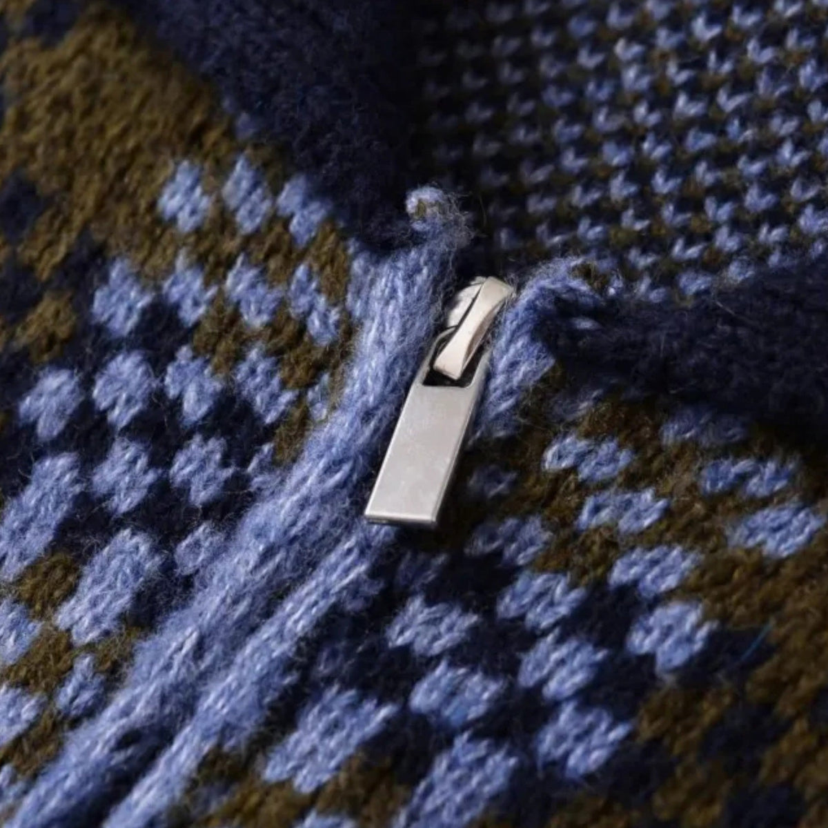 Nahaufnahme silberner Reißverschluss auf blau-brauner karierter Strickjacke | HauteBerlin