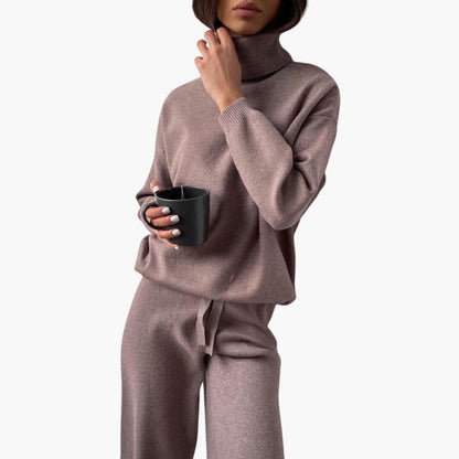 Strick-Zweiteiler für Damen in Taupe mit Rollkragen und weiter Hose, mit einer Tasse in der Hand